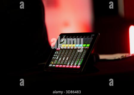 Tablet based mixing console showing multiple audio channels and meters, capturing the technical setup behind contemporary event production, livestream Stock Photo