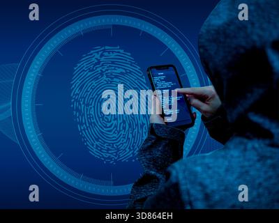 Hooded hacker holding a smartphone with code on the screen in front of a large digital fingerprint scanner interface. Concept of biometric identity th Stock Photo