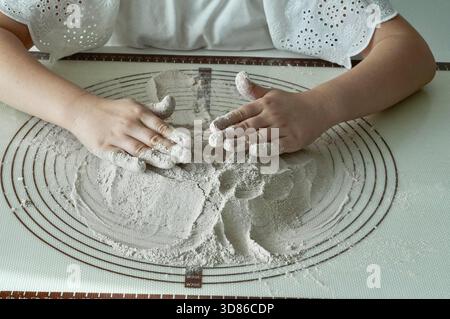 Children's hands knead the dough on a table in the kitchen Stock Photo