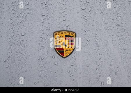 Porsche logo on the rain covered bonnet of a Porsche Taycan GTS. Stock Photo