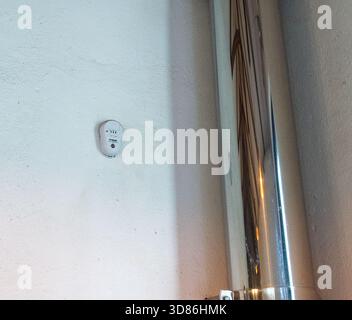 A Firehawk carbon monoxide alarm mounted too close to a flue pipe for a wood stove. Not installed correctly should be 1m to 3m away Stock Photo
