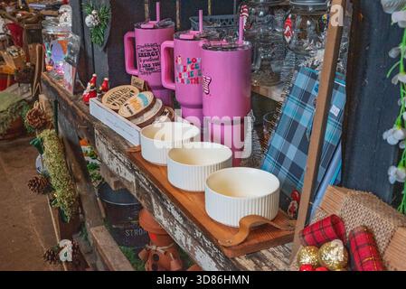 A festive display of Christmas-themed items, including pink tumblers, wooden coasters, and decorative pinecones, arranged on rustic wooden shelves. Stock Photo