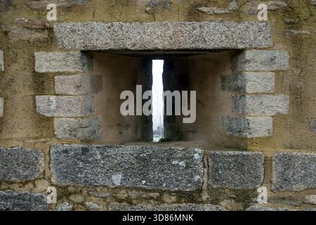 Arrowslit in fortified wall on harbour in Brittany, France Stock Photo