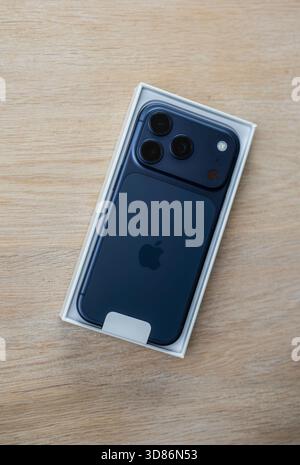 New black iPhone 17 pro smartphone with triple-lens camera placed in its original box on a wooden surface Stock Photo