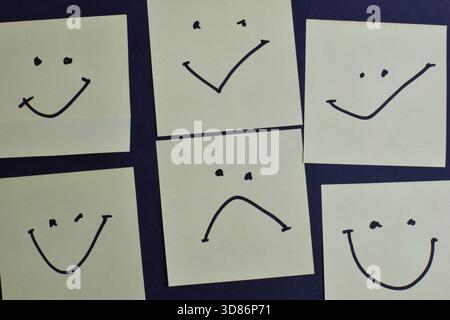 Six sticky notes with varied facial expressions on dark background, highlighting emotional diversity through simple design and layout. Stock Photo
