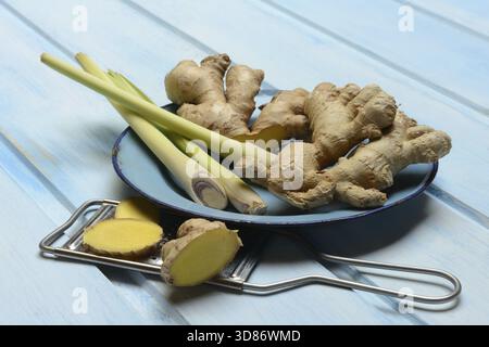 Ginger tubers and lemongrass on plate, grater with ginger pieces Stock Photo