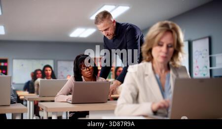 Computer Lab Professor Teaches Diverse Group Of Students Various Languages. Stock Photo