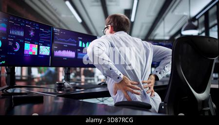 Man With Bad Posture Suffering From Back Pain In Office. Stock Photo