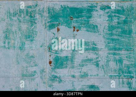 Weathered metal surface displays intricate rust patterns and textures on an outdoor wall. Natural lighting highlights the rustic charm and aged character of the material. Stock Photo