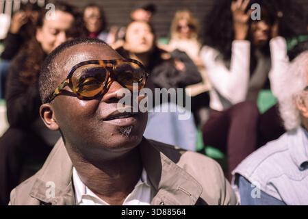 Disappointed mature man wearing eyeglasses at stadium stand on sunny day Stock Photo