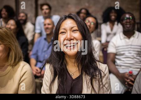Smiling long haired mature woman enjoying play in stage theater Stock Photo