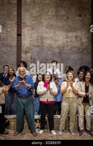 Full length of happy senior male and female spectators giving standing ovation with audience at stage theater Stock Photo