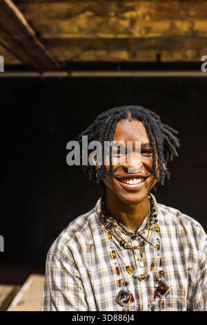 Portrait of smiling young man with braided hair wearing jewelry Stock Photo