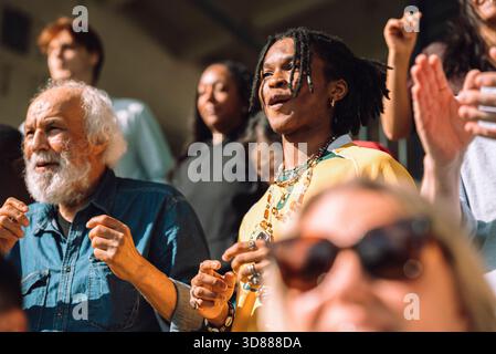 Low angle view of young man cheering while standing in sports stadium stand and watching game Stock Photo