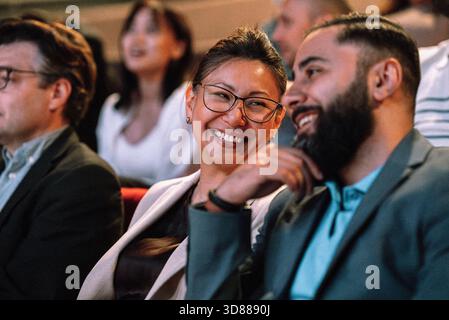 Smiling mature woman talking with male friend while sitting in stage theater Stock Photo