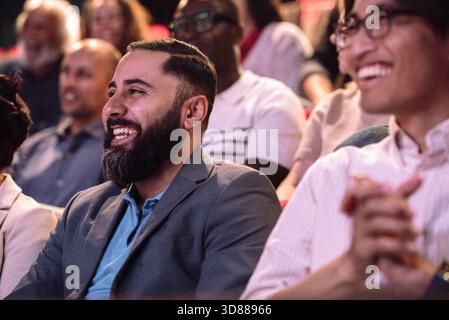 Happy bearded man enjoying stage play while sitting in theater Stock Photo