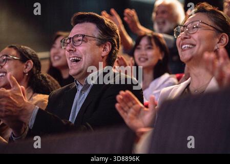 Cheerful mature man clapping with sitting with audience in stage theater Stock Photo