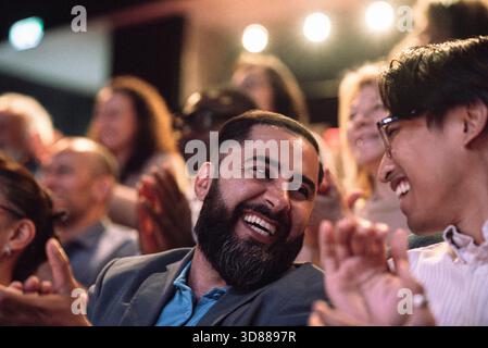 Happy bearded man clapping while enjoying with male friend in stage theater Stock Photo