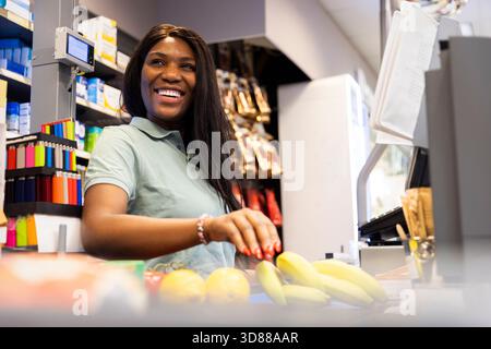 Low angle view of happy female cashier working at checkout counter in supermarket Stock Photo