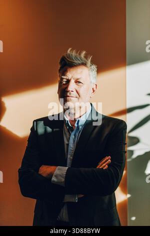 Senior businessman standing with arms crossed posing at office park ...