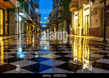 Pedestrian shopping street Via Firenze in central Pescara, Italy, with Christmas lights and wet reflections at twilight. Stock Photo