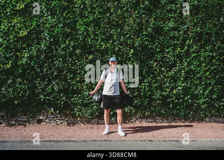 Portrait of smiling male golfer standing in front of bush at sunny day Stock Photo