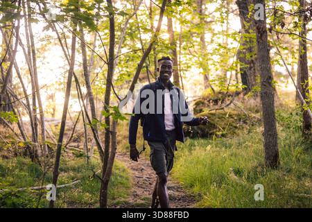 Portrait of smiling man walking on dirt road while exploring forest Stock Photo