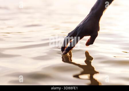 Hand of man touching water of lake Stock Photo