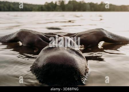 Headshot of relaxed man lying in water at lake Stock Photo