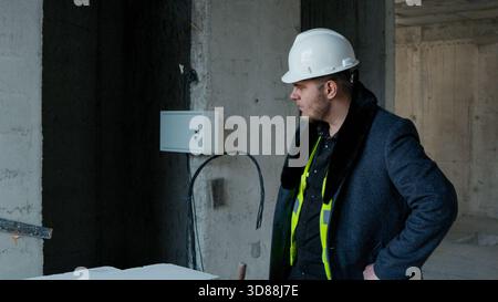 A construction worker in a helmet reviewing plans or measurements inside  Stock Photo