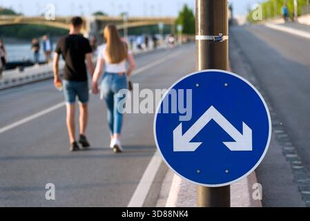 Way fork sign. defocused young couple walking hand in hand Stock Photo