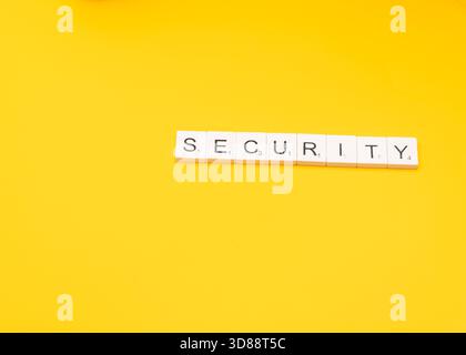 word tiles spell out the word SECURITY on a bright yellow background, suggesting a focus on safety and protection. Stock Photo