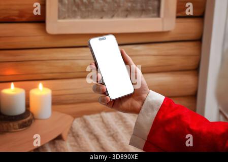 Hand holding smartphone with blank screen in warm Christmas interior, ideal for holiday marketing, festive mockups, mobile app previews and seasonal d Stock Photo