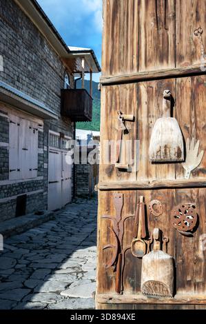 Weathered wooden blacksmith shop door in Lahij, Azerbaijan, with rustic metal tools and handmade details. Stock Photo