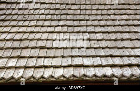 Weathered wooden shingles forming a rustic, horizontal roof texture with aged brown and gray tones, showing worn craftsmanship ideal for historical scenes Stock Photo