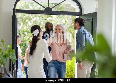Guests arriving at wedding, greeting bride with smiles and gift at entrance. celebration, happiness, ceremony, arrival, festive || Model released Stock Photo