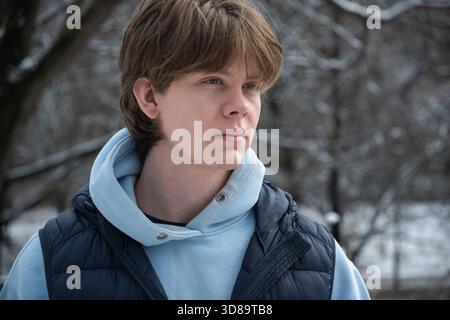 Closeup of caucasian handsome young man standing outdoors in winter snow park. Outdoor Lifestyle Stock Photo