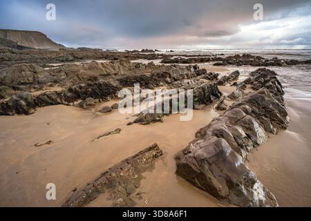 Dramatic storm clouds gathering at dawn on Cornish beach in mid winter Stock Photo