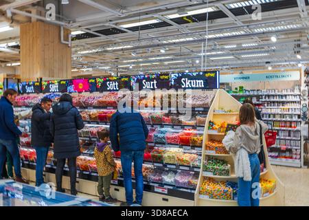 Beautiful view of shoppers choosing colorful candy in a supermarket sweets section. Sweden. Uppsala. Stock Photo