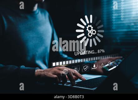 Software Update and System Upgrade Concept. Person holding phone while using laptop with software update progress interface and security, technology m Stock Photo