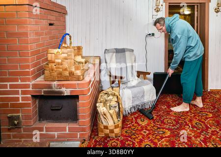 Refreshing surface as homeowner uses vacuum in room with stove heating, creating tidy environment during regular household routine. Stock Photo