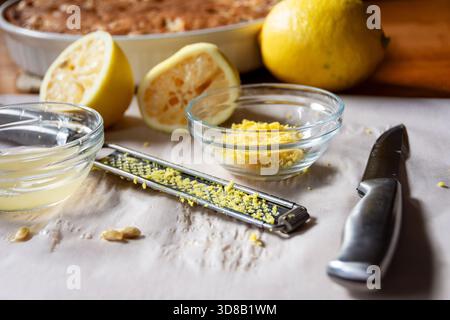 Preparing fresh lemon glaze: zest, juice, lemon rinds, and microplane near the baked cranberry cake. Natural, homemade food preparation. Stock Photo