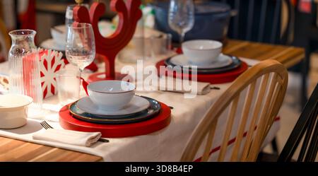 Elegant Holiday Table Setting with Red Placemats White Dishes and Festive Decorations for Christmas Dinner Celebration Stock Photo