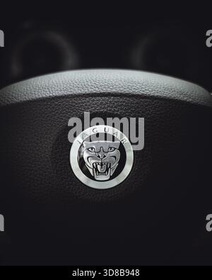 Jaguar steering wheel with embossed Jaguar logo, close-up of luxury car interior. Stock Photo
