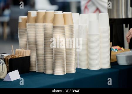 Stacks of disposable paper and plastic cups neatly arranged on a beverage station table prepared for event guests in a clean and organized indoor serv Stock Photo
