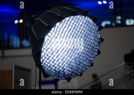 Professional LED softbox with honeycomb grid attachment mounted on a light stand, providing controlled directional lighting for event production Stock Photo