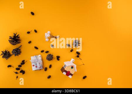 Flat lay of pinecones, small gift box, and holiday decor on a yellow background. A simple and warm composition that evokes the Christmas spirit. Stock Photo