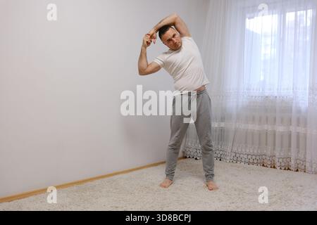 A middle-aged man stretching after waking up in a modern bedroom interior. High quality photo Stock Photo