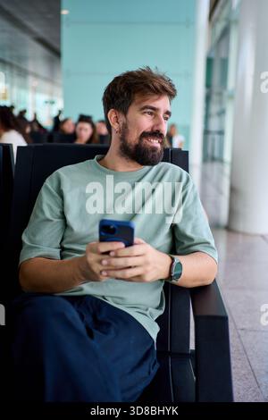 Smiling man using smartphone at airport gate Stock Photo