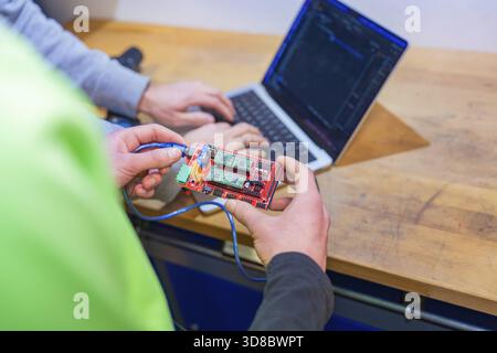 Circuit board is held while someone is working on a laptop, Jugend Forschungszentrum Nagold, Calw district, Germany Stock Photo